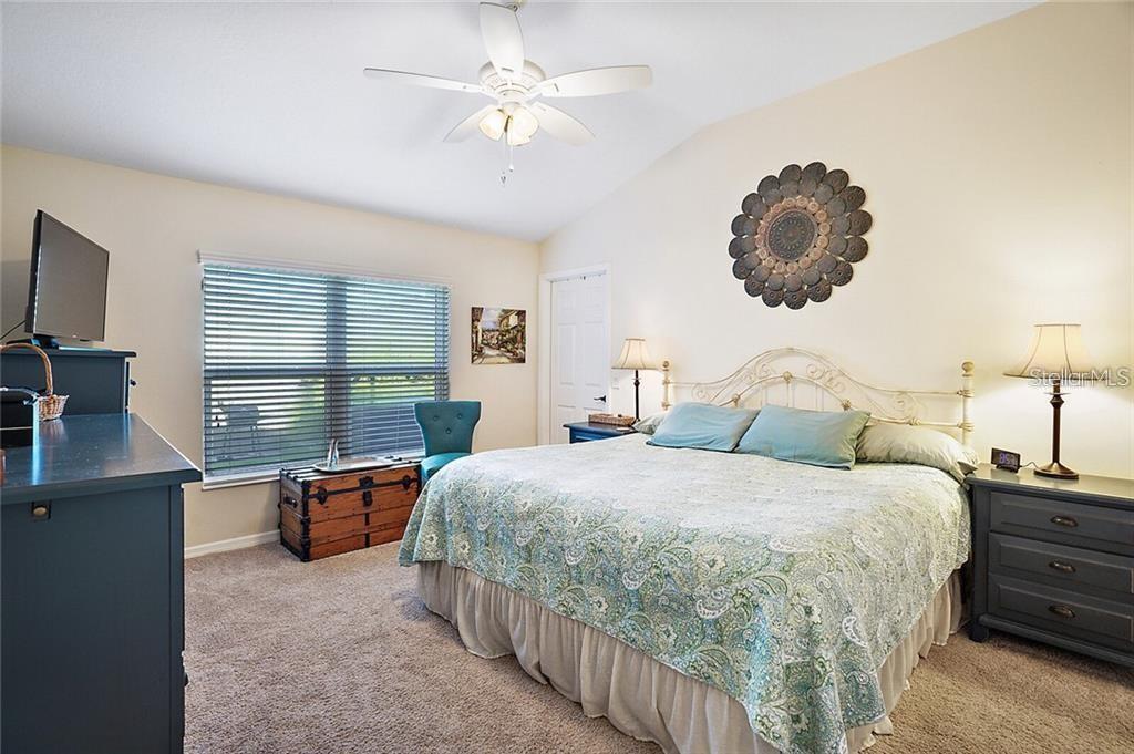 A bedroom features a king-sized bed, a ceiling fan, a window, and dark wooden furniture — 3225 WISE WAY, THE VILLAGES, FL