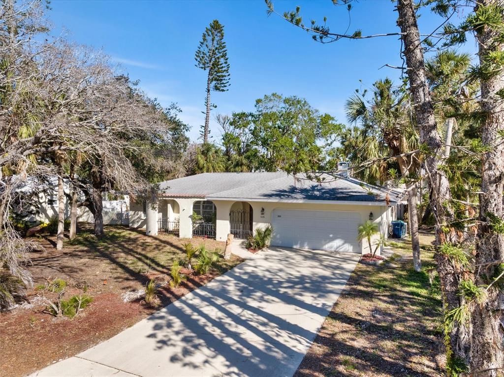 A single-story house with a white exterior, a two-car garage, and a concrete driveway — 5151 OAKMONT PLACE, SARASOTA, FL