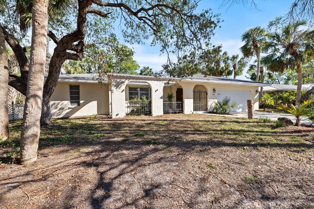 A single-story house with a white stucco facade, arched entryways, and a two-car garage — 5151 OAKMONT PLACE, SARASOTA, FL