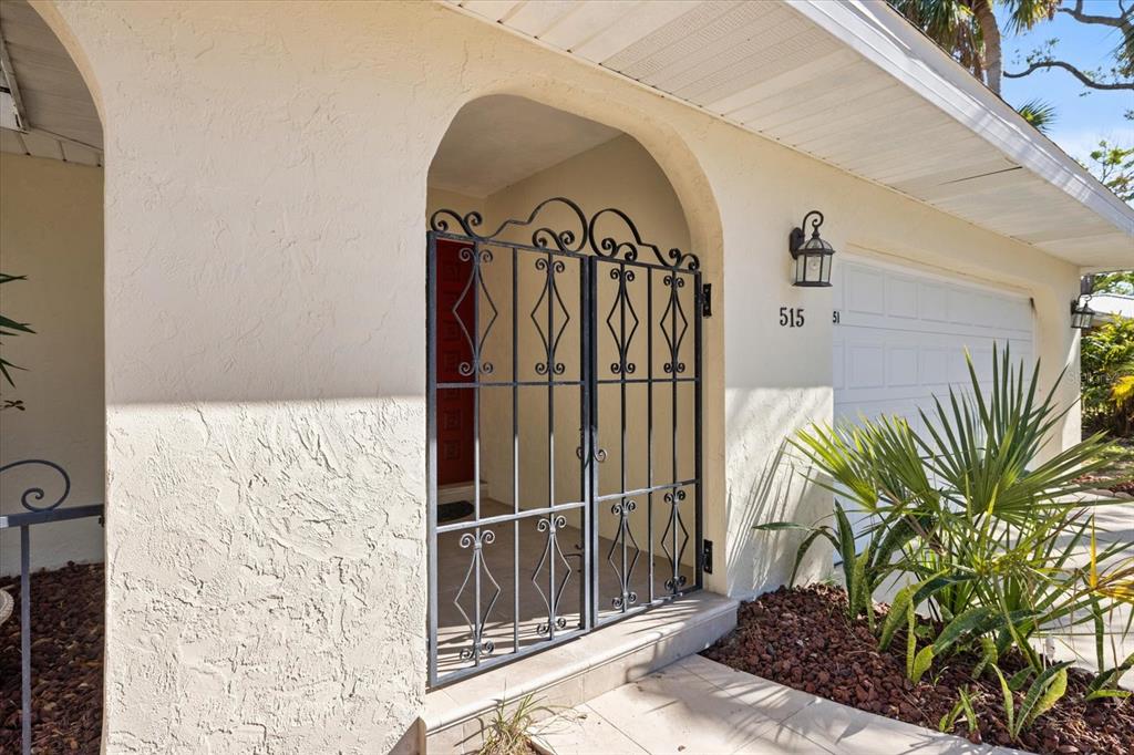 A metal security gate stands at the entrance of a house with a stucco exterior — 5151 OAKMONT PLACE, SARASOTA, FL