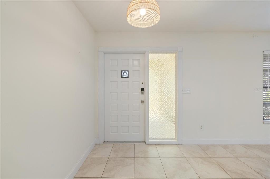An entryway features a white door with a glass panel, tile flooring, and a pendant light — 5151 OAKMONT PLACE, SARASOTA, FL