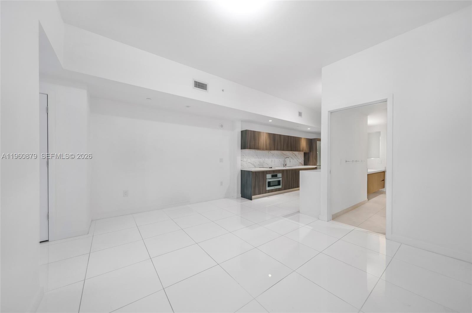 This room features white tile flooring, a minimalist kitchen with dark cabinetry, and white walls — 851 NE 1st Ave # 204, Miami FL 33132, MIAMI, FL