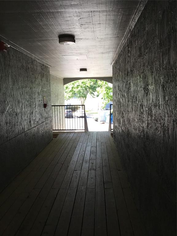 A covered wooden walkway leads toward an arched opening with a view of a parking lot — 3705 SW 27TH STREET UNIT 422, GAINESVILLE, FL