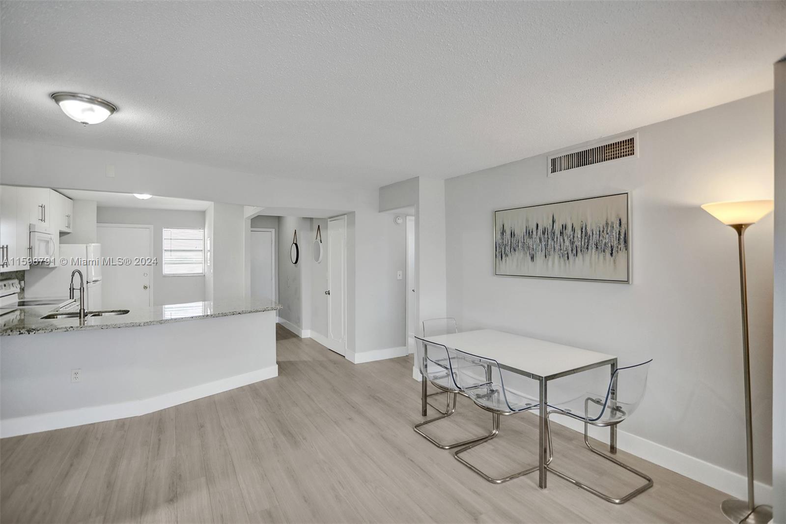 A dining area with a white table and clear chairs sits next to a kitchen — 1770 NE 191st St # 1, Miami FL 33179, MIAMI, FL