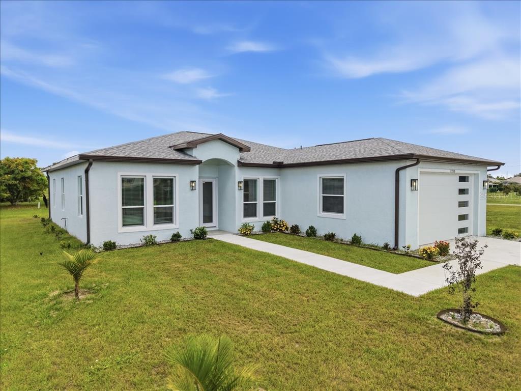 A light blue single-story house with a white garage door and a concrete walkway — 1215 RIO DE JANEIRO AVENUE, PUNTA GORDA, FL