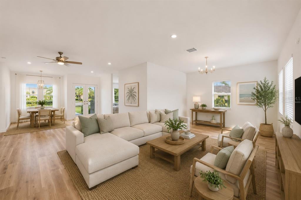 A bright, open-concept living and dining area features light wood flooring and neutral-toned furniture — 1215 RIO DE JANEIRO AVENUE, PUNTA GORDA, FL