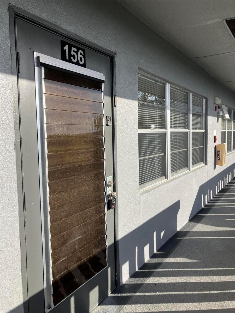 An exterior view of a gray door numbered 156 with a brown louvered window insert — 156 Suffolk D, Boca Raton FL 33434, BOCA RATON, FL