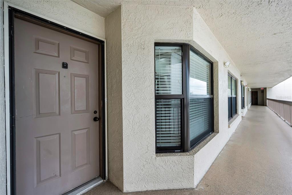 An exterior view of a building corridor featuring a brown door and a bay window — 1324 PASADENA AVENUE S UNIT 605, ST PETERSBURG, FL
