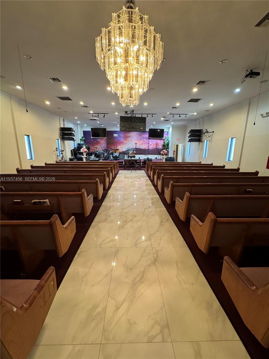 A church sanctuary features rows of wooden pews, a marble-tiled aisle, and a large crystal chandelier — 1595 NW 119th St, North Miami FL 33167, NORTH MIAMI, FL