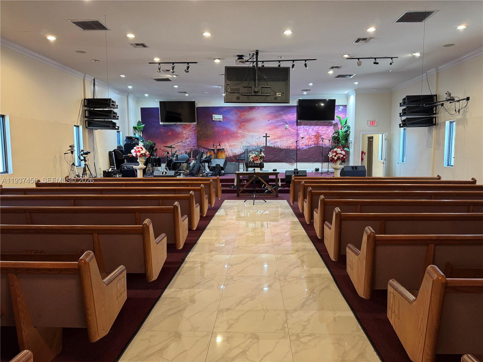 A church sanctuary features rows of wooden pews, a central aisle, and a stage area — 1595 NW 119th St, North Miami FL 33167, NORTH MIAMI, FL