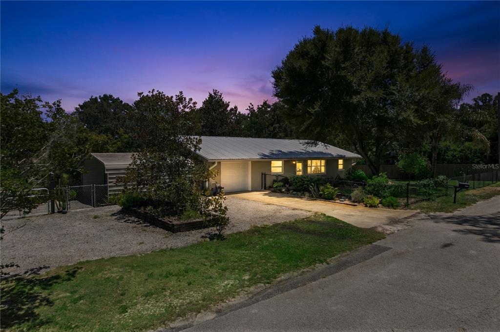 A single-story house with a metal roof and attached garage at twilight — 37400 SAINT LOUIS AVENUE, UMATILLA, FL