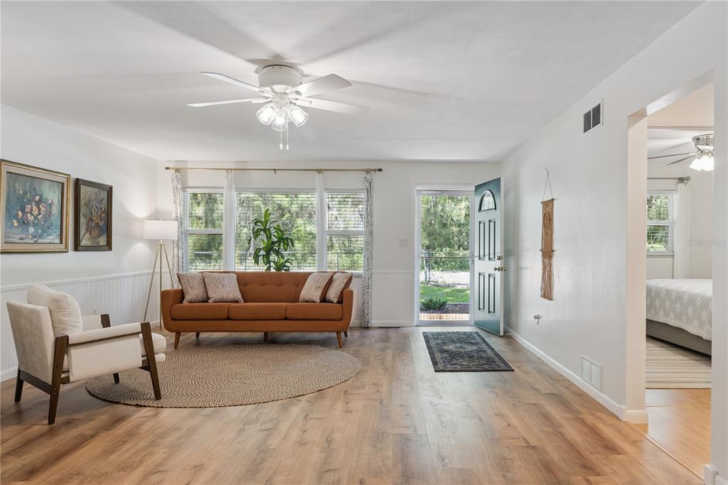 A living room features wood-look flooring, a brown sofa, a white armchair, and a front door — 37400 SAINT LOUIS AVENUE, UMATILLA, FL