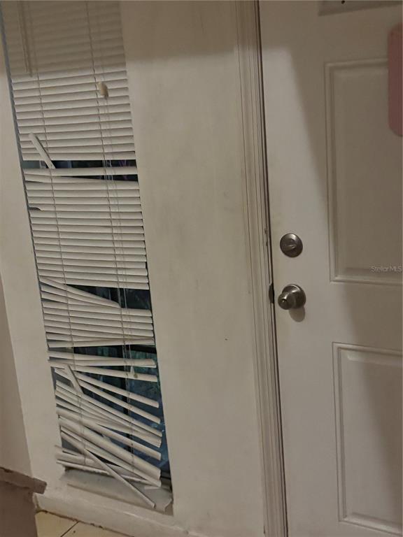 A white door with a deadbolt and knob sits next to a damaged window blind — 3401 SUNRISE VILLAS COURT S, TAMPA, FL