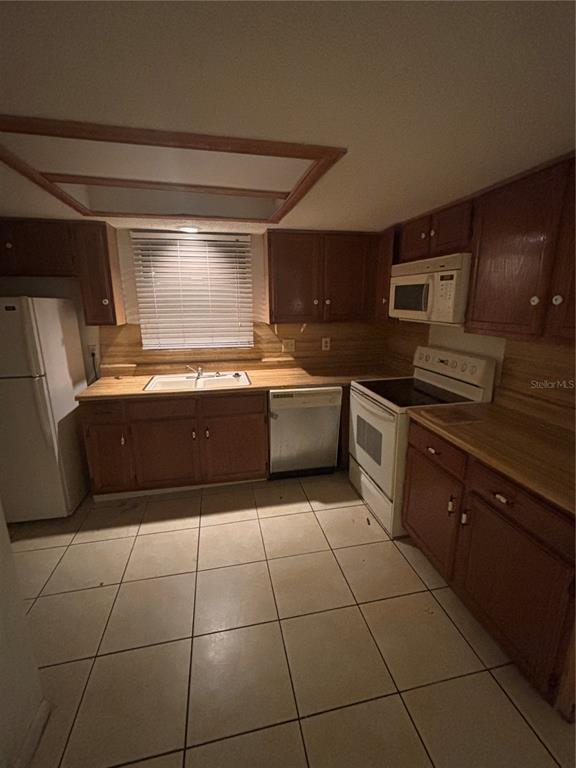 A kitchen features wood cabinets, laminate countertops, white appliances, and light-colored tile flooring — 3401 SUNRISE VILLAS COURT S, TAMPA, FL