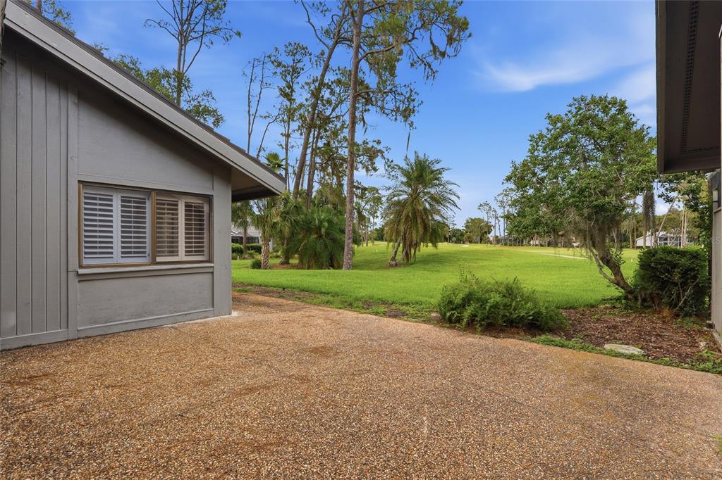 A view of a patio overlooking a grassy golf course with trees and a house exterior — 5434 KEMKERRY ROAD, WESLEY CHAPEL, FL