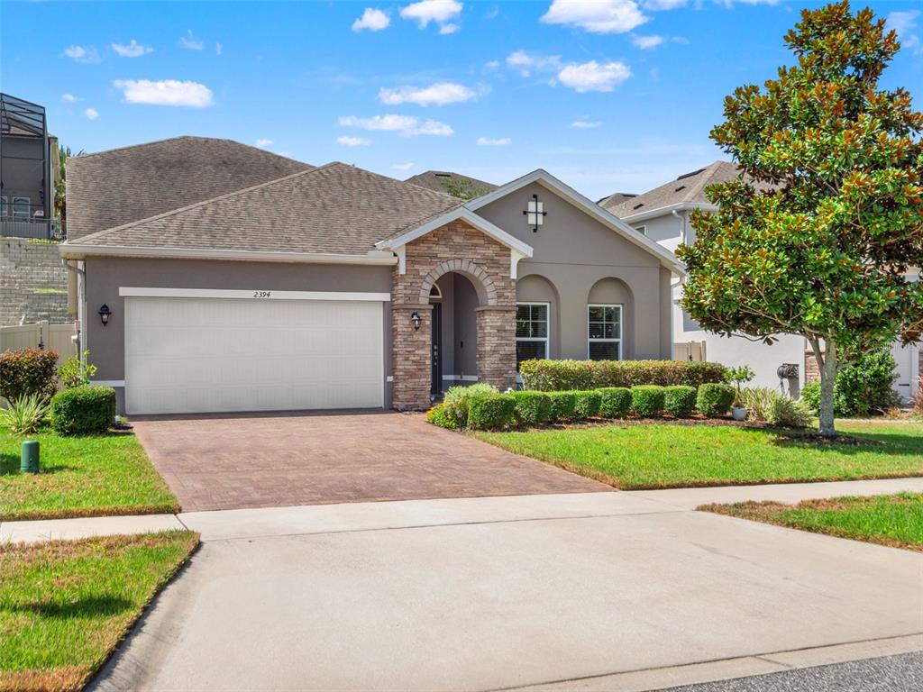 A single-story house features a stone-accented entryway, a two-car garage, and a landscaped front yard — 2394 HASTINGS BOULEVARD, CLERMONT, FL