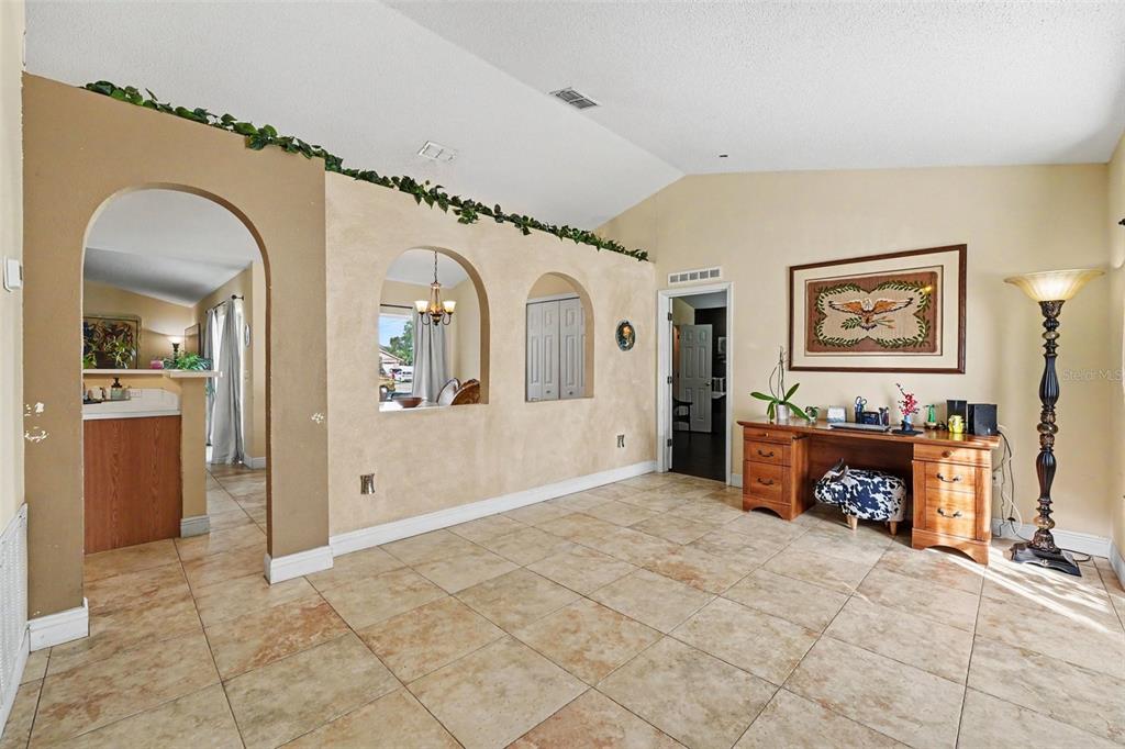 A tiled room features an arched entryway, decorative wall cutouts, and a wooden desk — 807 DEL PRADO DRIVE, KISSIMMEE, FL
