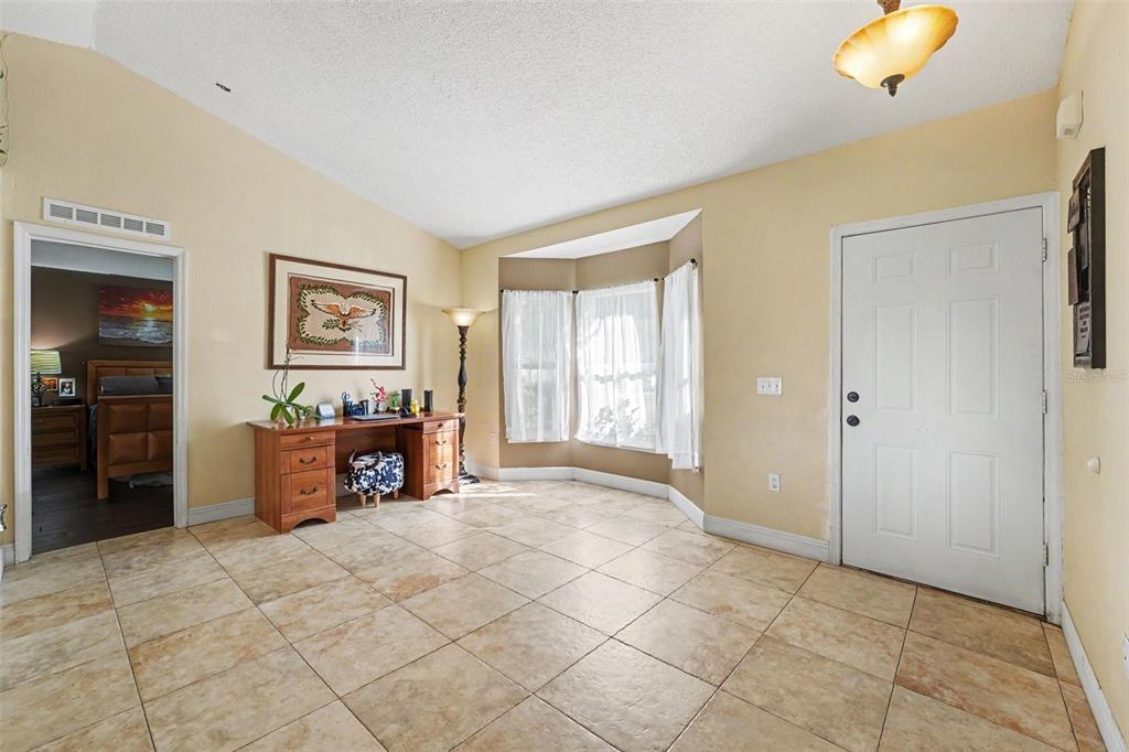 A room with tile flooring, a wooden desk, a bay window, and a white door — 807 DEL PRADO DRIVE, KISSIMMEE, FL