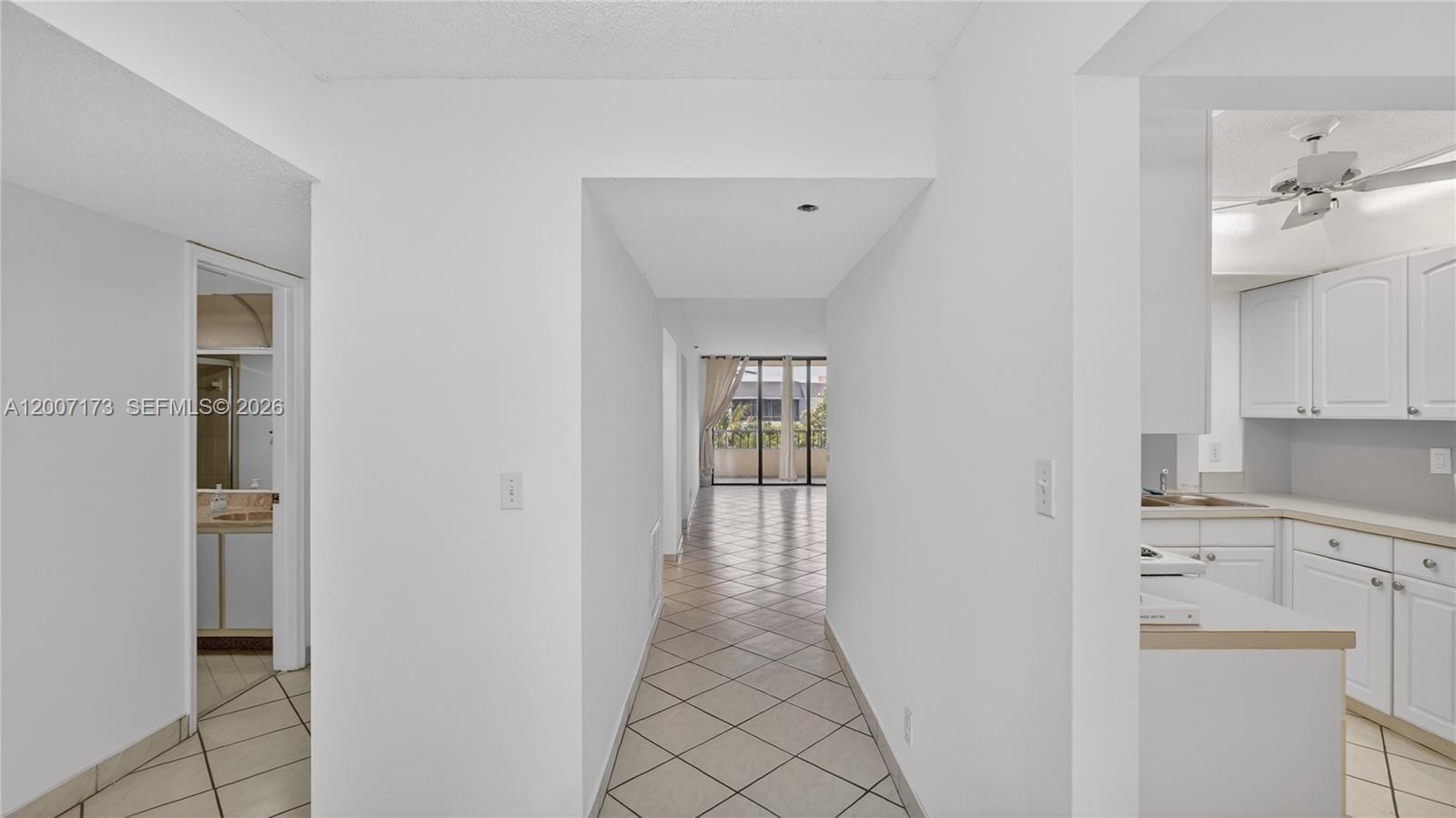 A hallway with tile floors leads from a kitchen toward a balcony with sliding doors — 1850 Homewood Blvd # 5010, Delray Beach FL 33445, DELRAY BEACH, FL