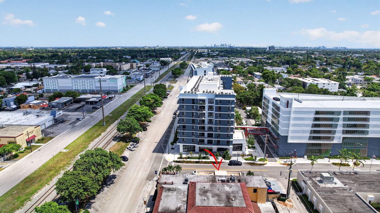 An aerial view shows a multi-story apartment building next to a commercial structure and railroad tracks — 2040 Polk Street, Hollywood FL 33020, HOLLYWOOD, FL