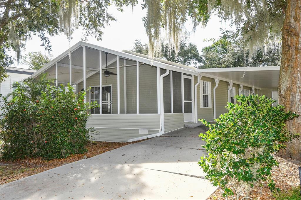 A light green mobile home with a screened-in porch and a concrete driveway — 11642 MARTELL COURT, LEESBURG, FL
