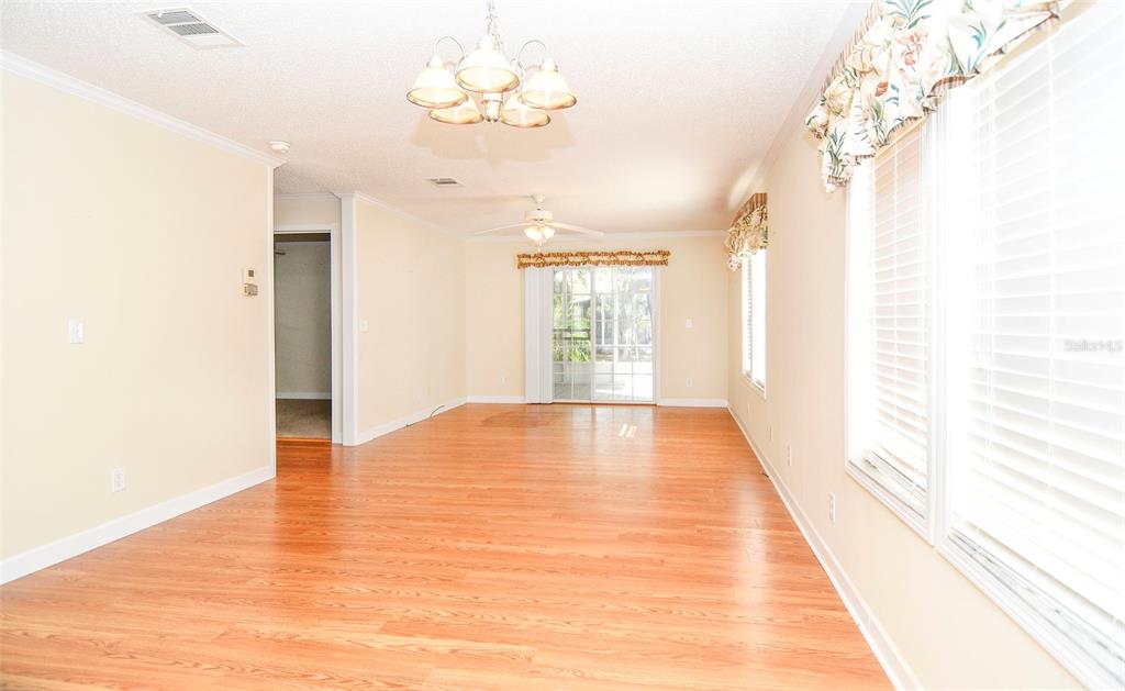 A living room with light-colored walls, wood-look flooring, a ceiling fan, and sliding glass doors — 11642 MARTELL COURT, LEESBURG, FL