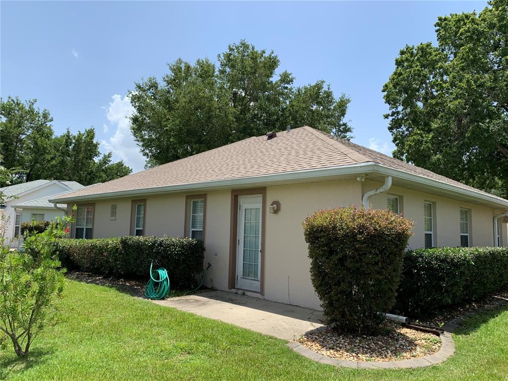 A beige, single-story house with a hip roof, white trim, and surrounding landscaping — 6369 SW 117TH LOOP, OCALA, FL