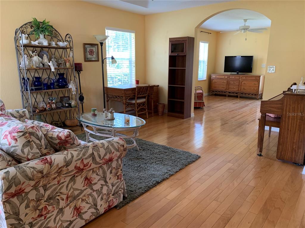A living room features hardwood floors, a floral sofa, a glass coffee table, and a piano — 6369 SW 117TH LOOP, OCALA, FL
