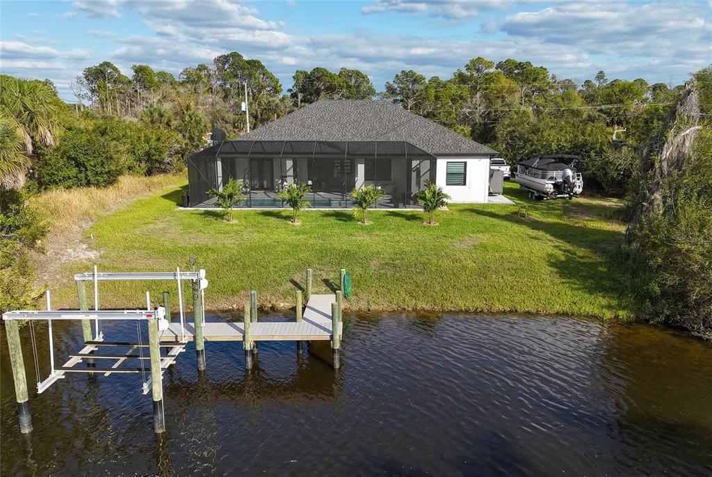 An aerial view of a waterfront house with a screened pool enclosure and boat dock — 1015 HOFFER STREET, PORT CHARLOTTE, FL