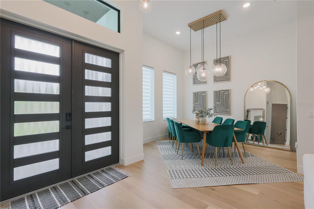 A modern dining room features green velvet chairs, a wooden table, and a large arched mirror — 1015 HOFFER STREET, PORT CHARLOTTE, FL