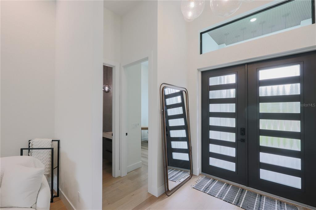 An entryway with double glass-paneled doors, a tall floor mirror, and light wood flooring — 1015 HOFFER STREET, PORT CHARLOTTE, FL