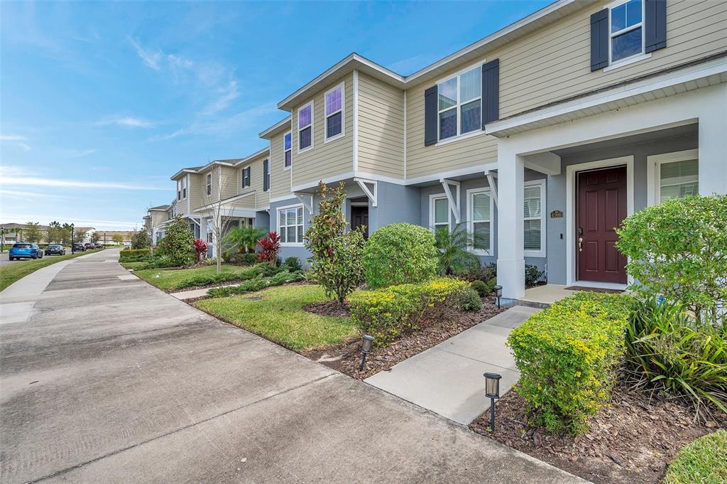 A row of two-story townhouses with beige siding, gray lower levels, and small front yards — 4966 AVALON PARK BOULEVARD, WESLEY CHAPEL, FL