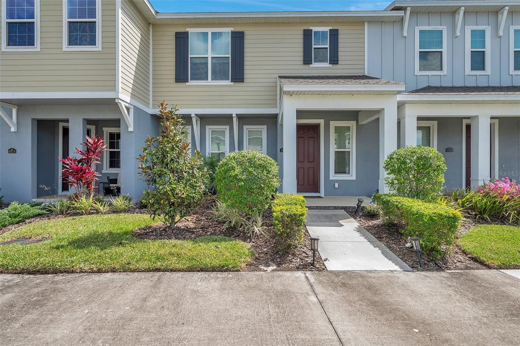 The exterior of a two-story townhouse features a covered entryway and a concrete walkway — 4966 AVALON PARK BOULEVARD, WESLEY CHAPEL, FL