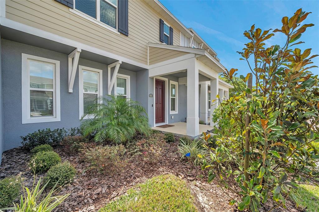 The exterior of a two-story townhouse features gray stucco, tan siding, and a covered porch — 4966 AVALON PARK BOULEVARD, WESLEY CHAPEL, FL