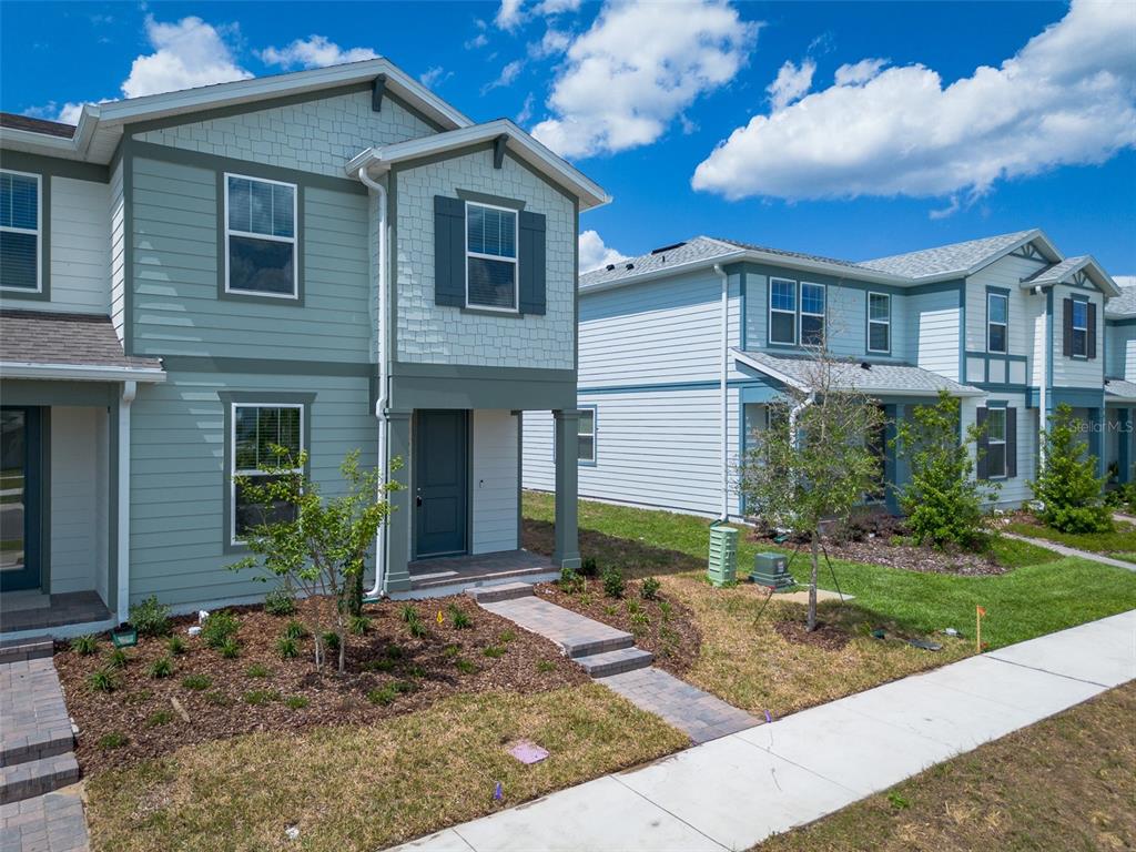 A two-story light green house with a paved walkway and small front yard — 4565 ORCHARD VIEW ALLEY, CLERMONT, FL