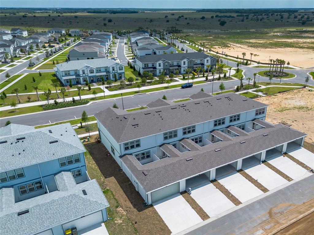 An aerial view shows a row of modern townhomes with attached garages and concrete driveways — 4565 ORCHARD VIEW ALLEY, CLERMONT, FL