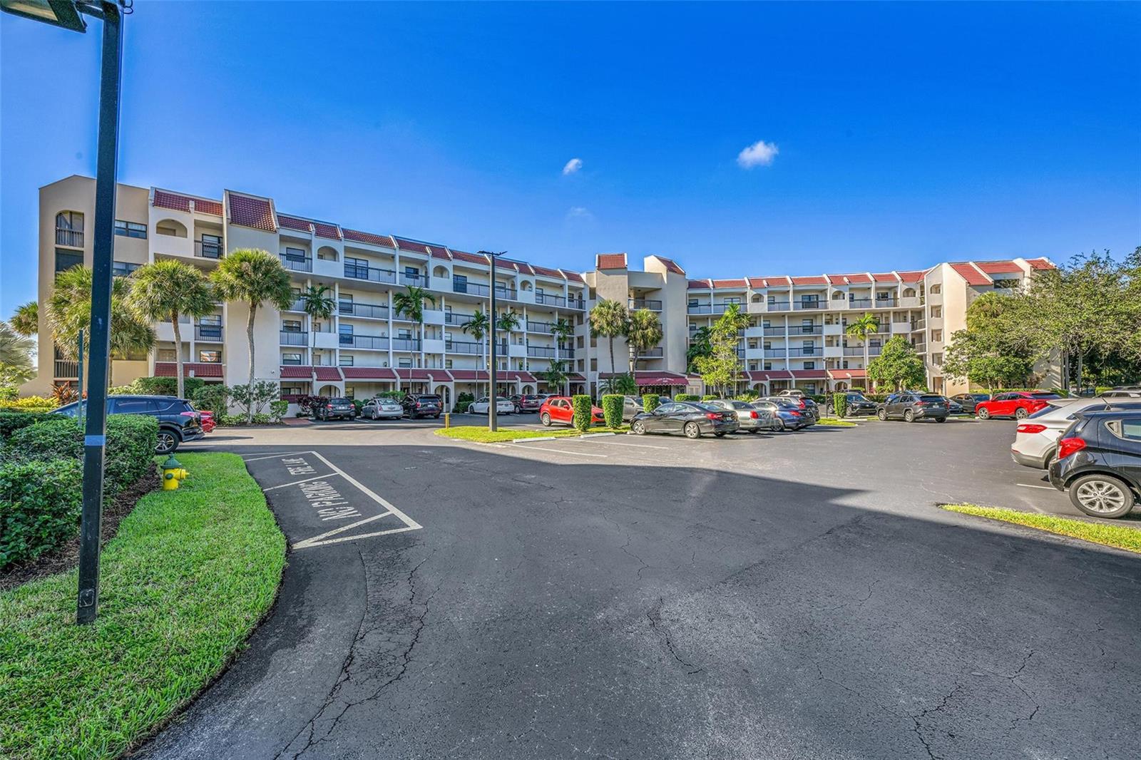 A multi-story apartment building with balconies stands behind a paved parking lot — 3591 Environ Boulevard # A305, Lauderhill FL 33319, LAUDERHILL, FL