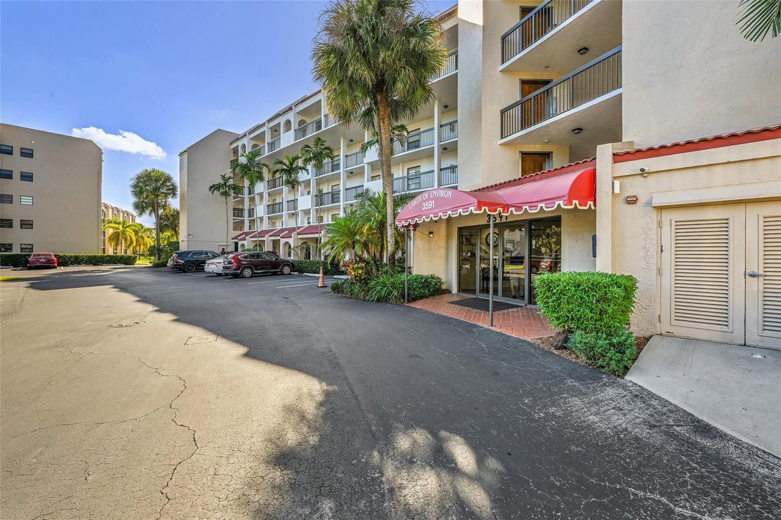 The exterior view shows a multi-story apartment building with a red awning over the entrance — 3591 Environ Boulevard # A305, Lauderhill FL 33319, LAUDERHILL, FL