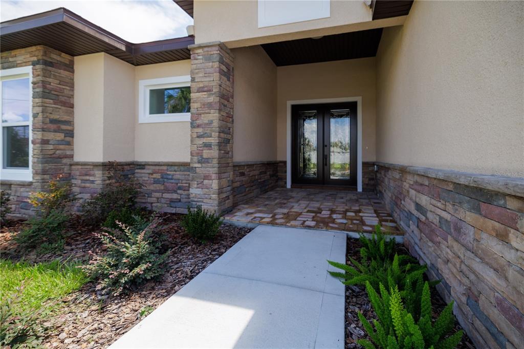 A concrete walkway leads to the front entrance of a house with stone veneer siding — 19 FRANCIS LANE, PALM COAST, FL
