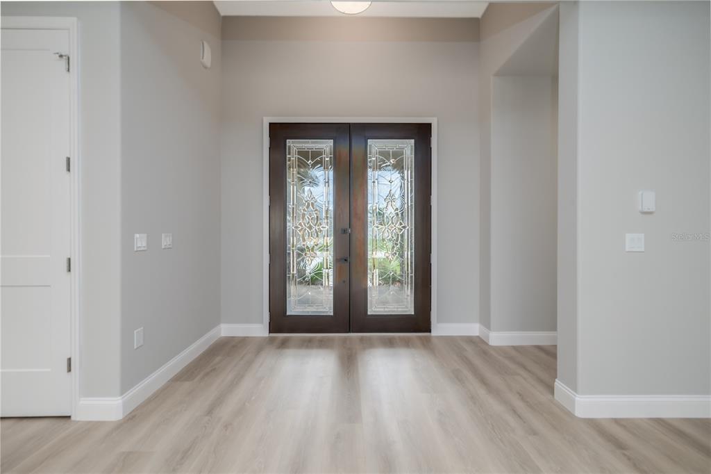 An entryway features light wood-look flooring, gray walls, and a dark wood double front door — 19 FRANCIS LANE, PALM COAST, FL