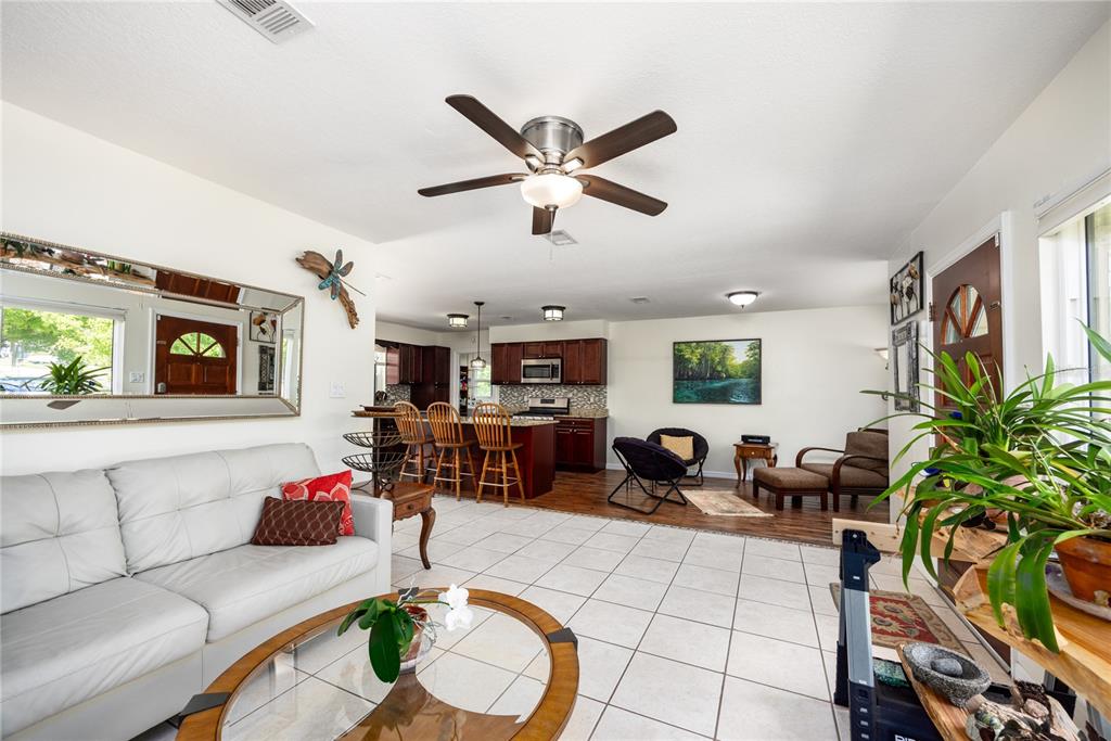 An open-concept living room and kitchen featuring tile flooring, a ceiling fan, and wood cabinetry — 5016 NW 36TH STREET, GAINESVILLE, FL