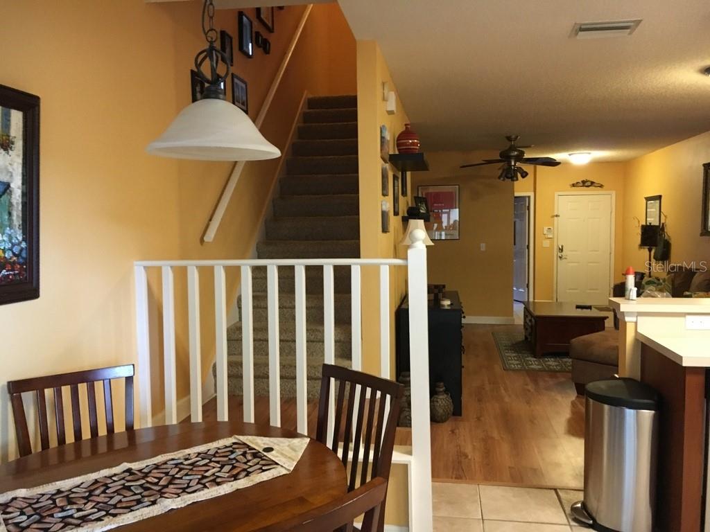 A dining area with a wooden table overlooks a carpeted staircase and a living room — 6448 OSPREY LAKE CIRCLE, RIVERVIEW, FL