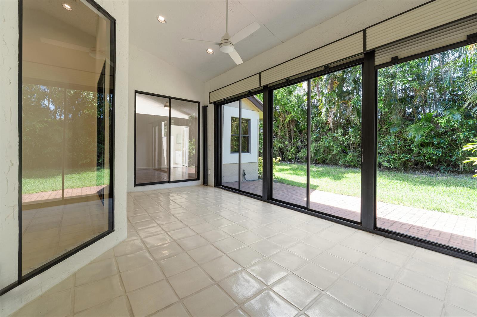 A sunroom with white tile flooring, a ceiling fan, and large sliding glass doors to outdoors — 7219 Le Chalet Boulevard, Boynton Beach FL 33472, BOYNTON BEACH, FL