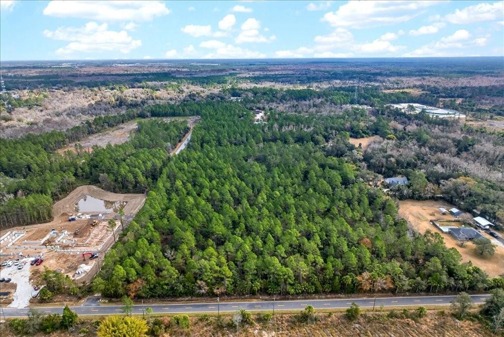 An aerial view shows a large, wooded plot of land adjacent to a paved road — 0 OLD HAW CREEK ROAD, BUNNELL, FL