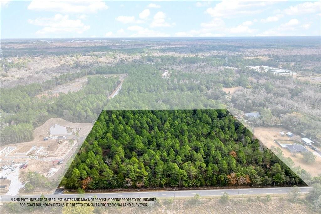 An aerial view shows a rectangular, wooded plot of land bordered by a paved road — 0 OLD HAW CREEK ROAD, BUNNELL, FL