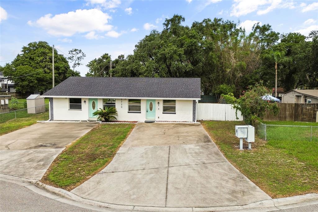 A single-story duplex with white exterior walls, two light blue doors, and two concrete driveways — 2720 S SUNRISE COURT UNIT 2, ORLANDO, FL
