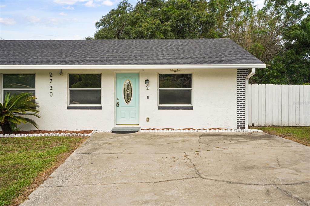 A single-story house with a white stucco exterior, a light blue front door, and driveway — 2720 S SUNRISE COURT UNIT 2, ORLANDO, FL