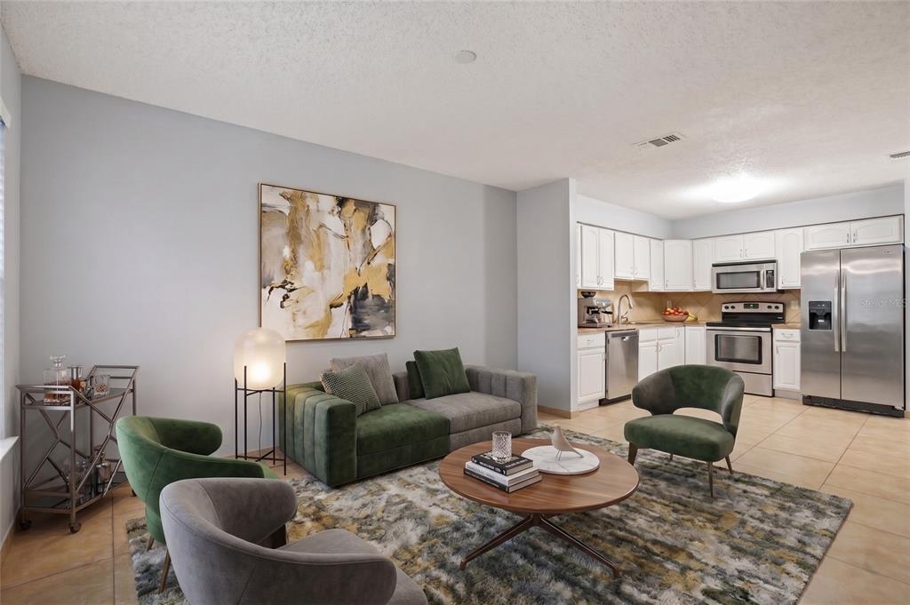 A living room with a green and gray sofa, accent chairs, and an open kitchen — 2720 S SUNRISE COURT UNIT 2, ORLANDO, FL