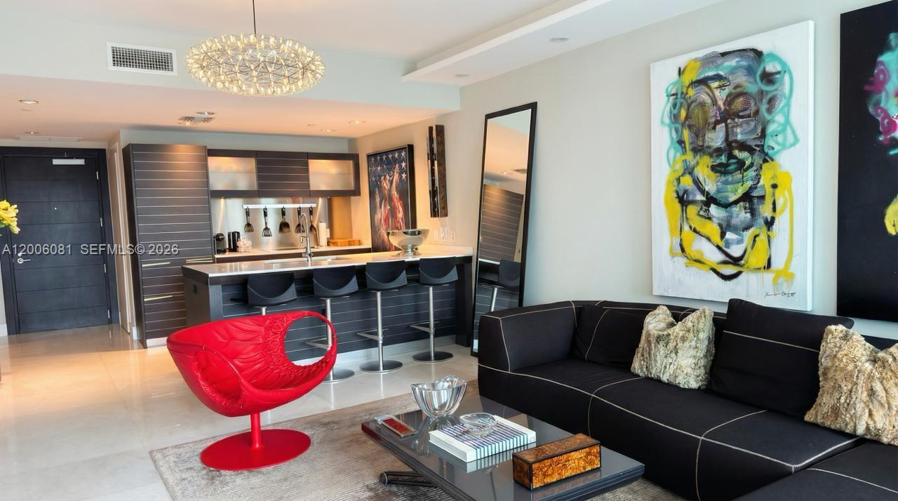 A modern living room features a black sofa, a red chair, and an open kitchen — 200 BISCAYNE BLVD WAY # 4310, Miami FL 33131, MIAMI, FL