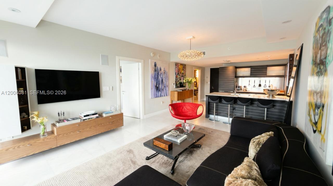 This open-concept living room features a modern kitchen, a black sofa, and white flooring — 200 BISCAYNE BLVD WAY # 4310, Miami FL 33131, MIAMI, FL